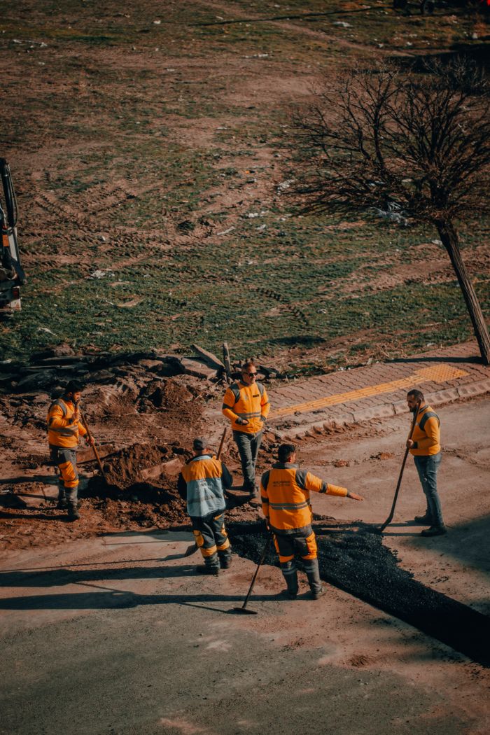 Group of road workers repairing asphalt in Kayseri, Turkey, in a sunny outdoor setting.